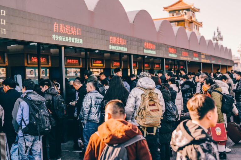 A crowd of people waiting in line at a ticket station in Beijing, China, showcasing modern urban life.