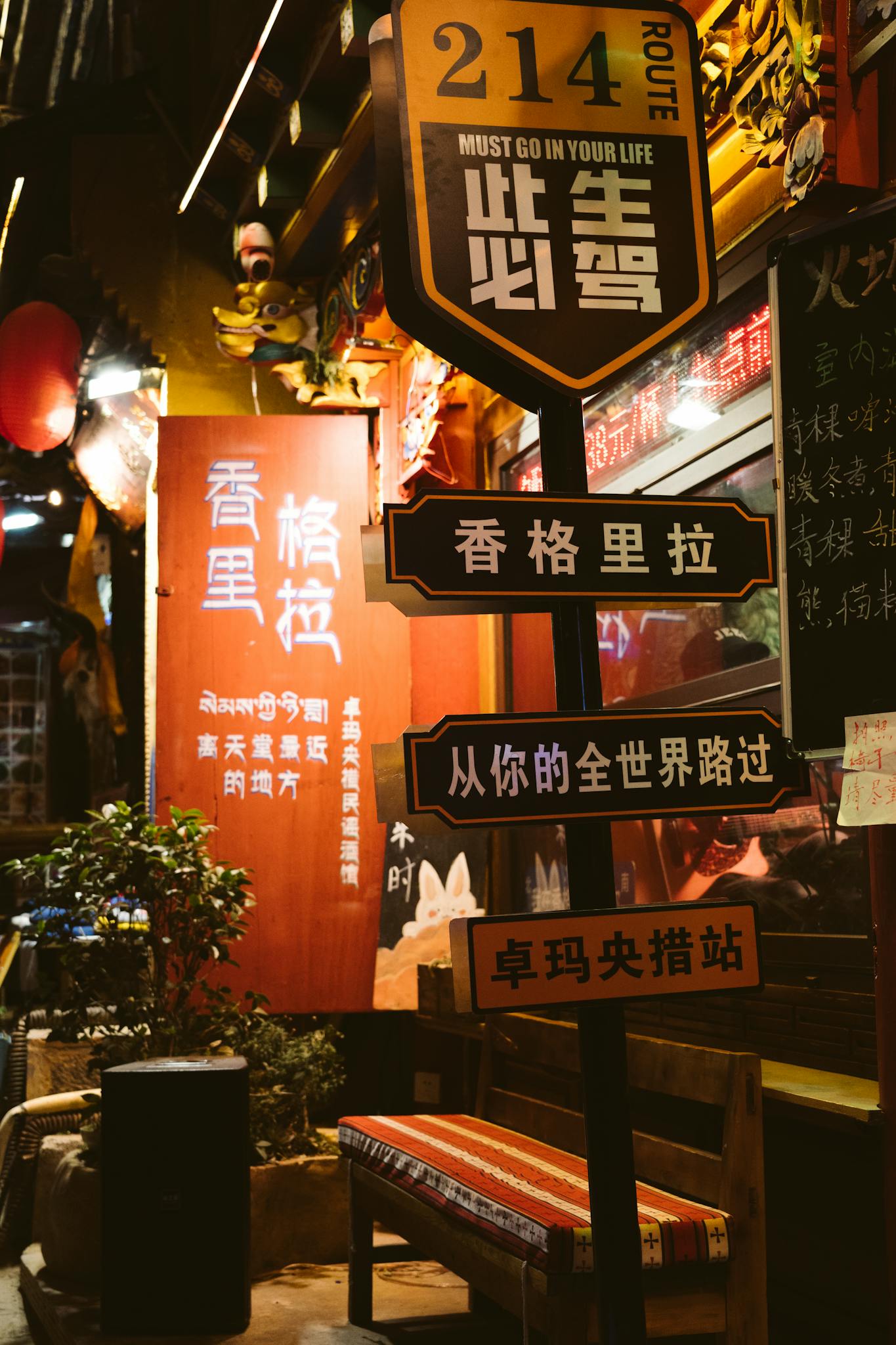 Traditional street scene with Chinese and English signs, vibrant night lights, and a cozy bench in an Asian setting.